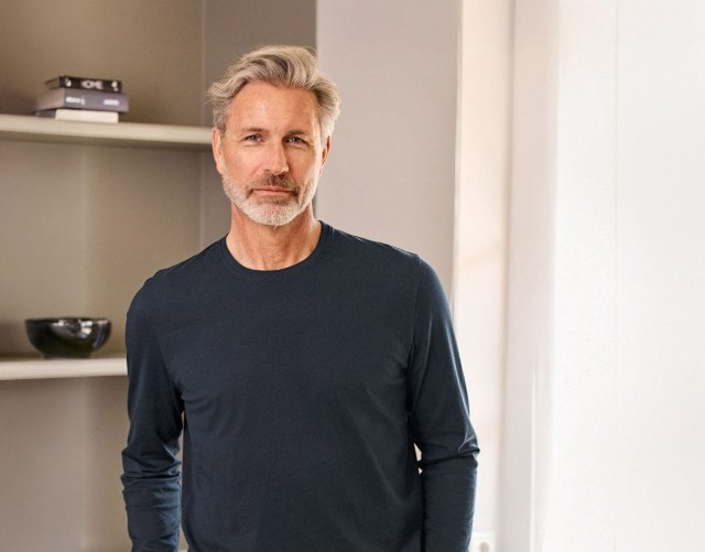 Charmanter Herr trägt einen klassischen, marine farbenen Pullover.