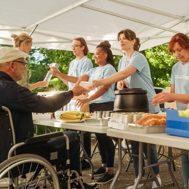 Ehrenamtliche Mitarbeiter verteilen warmes Essen und Obst. Ehrenamtliche Mitarbeiter verteilen warmes Essen und Obst.