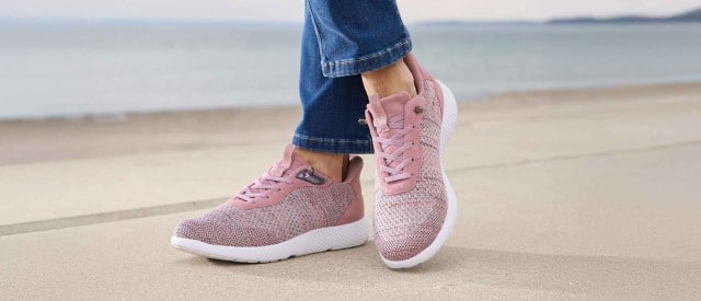 Dame am Strand trägt rosa Hallux-Schlupfschnürer. Dame am Strand trägt rosa Hallux-Schlupfschnürer.