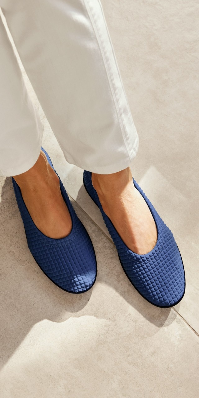 Damen in heller Hose trägt dunkelblaue Hallux-Slipper.