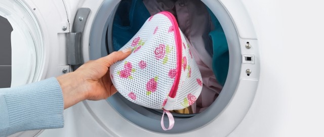 Wäschenetz mit Rosen-Print wird mit der übrigen Wäsche in die Waschmaschine gelegt.
