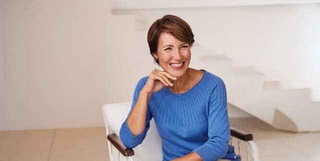 Lächelnde Frau im frischen blauen Pulli freut sich auf Ihre Fragen.