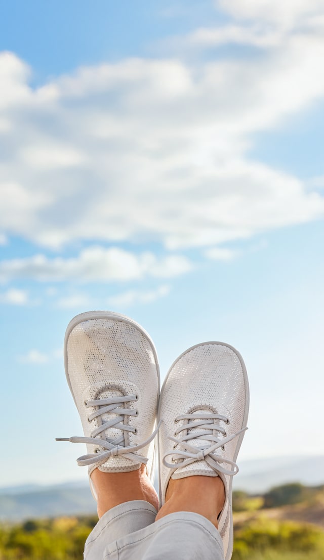 Die leichten Hallux-Softschnürer Naturform werden von einer Person getragen und in einer natürlichen Prärie die Luft gestreckt.
