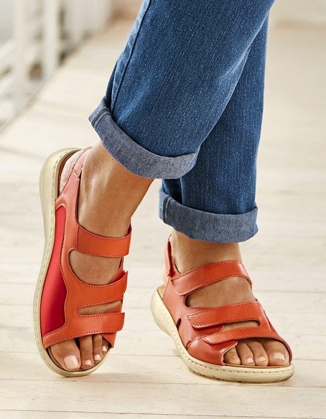 Hallux-Sandale Stretcheinsatz in orange wird sin sommerlicher Umgebung getragen.