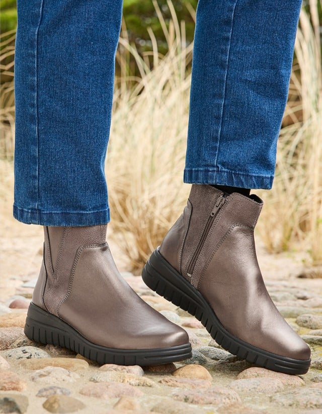 Dame trägt die goldenen Hallux-Stiefeletten Luftpolster.
