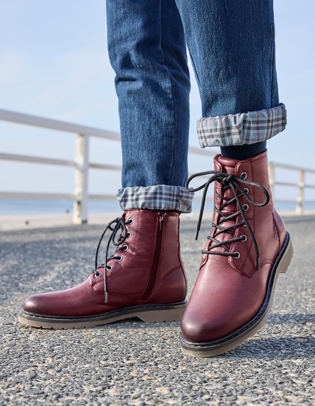 Dame trägt auf einer Strandpromenade den Hallux-Bootie Komfort in der Trend-Farbe Bordeaux.