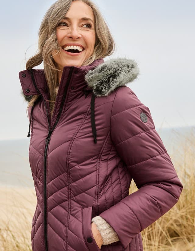 Dame spaziert mit der wunderbar warmen und leichten Steppjacke mit Webpelz-Kapuze.