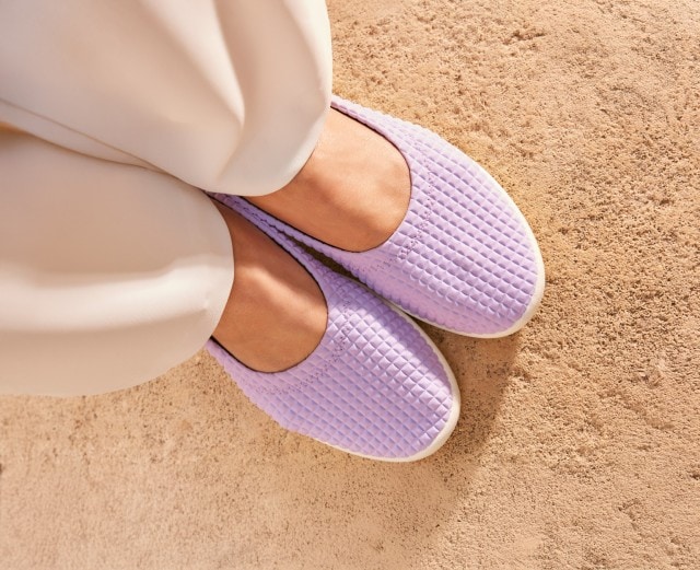 Dame trägt schöne, fliederfarbene Softslipper im Sommer am Pool.