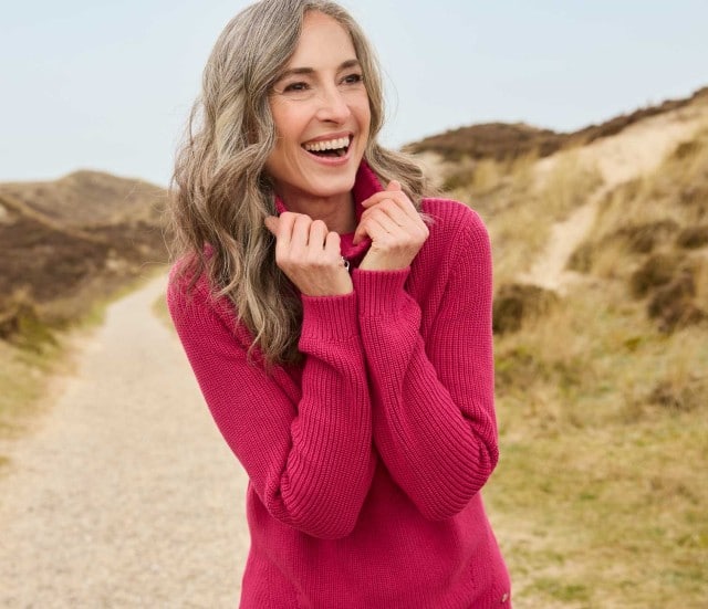 Dame spaziert zwischen den Dünen und trägt den gemütlichen Reißverschluss-Troyer Baumwolle in der Trendfarbe Bordeaux.