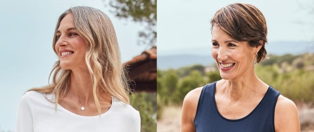 zwei Damen. Die eine trägt ein weißes Langarm-Shirt und die andere ein dunkelblaues Top. 