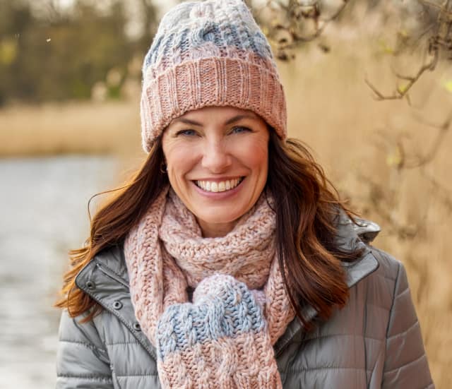 Dame trägt schöne und wärmende Strickmütze Zopfmuster