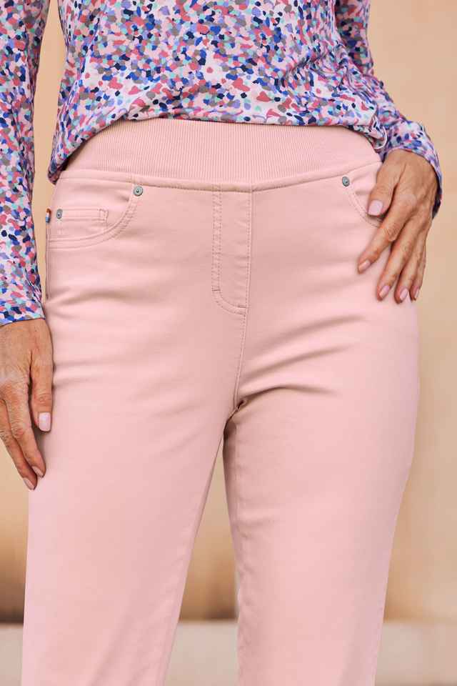 Ausschnitt einer rosa Hose und eines gemusterten Shirts.