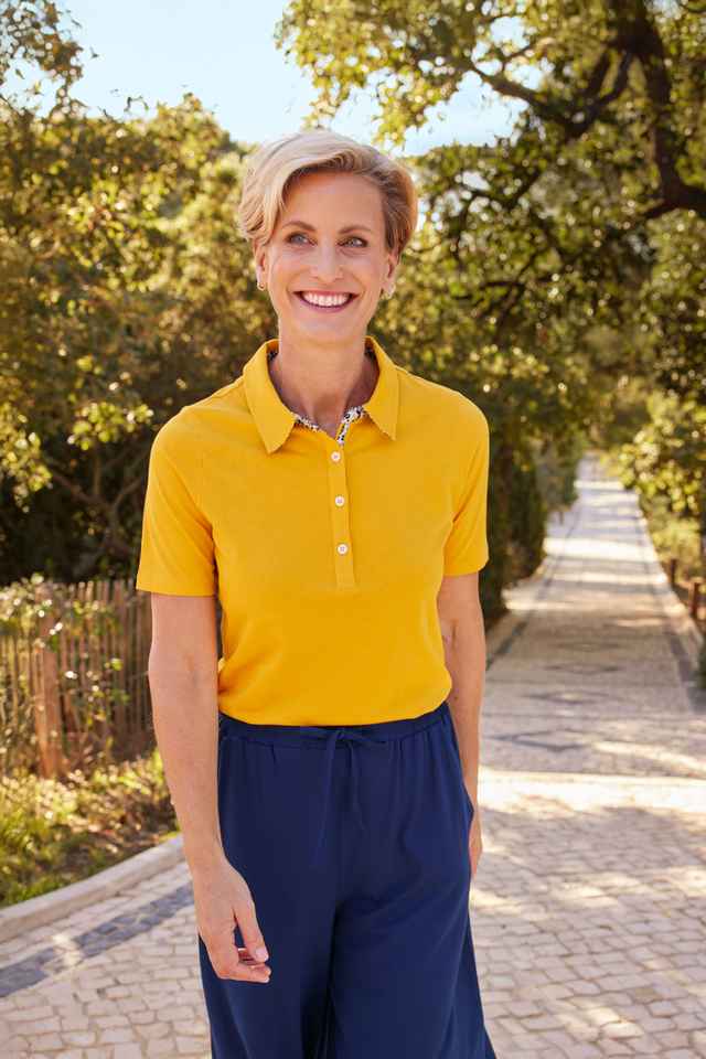 Frau trägt ein gelbes Poloshirt aus weicher Baumwolle.
