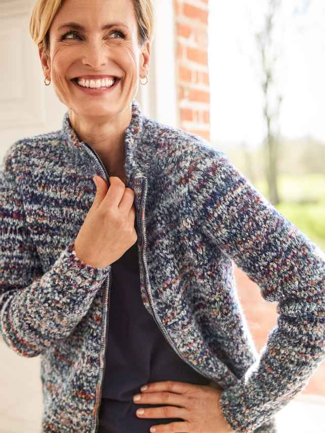 Anschnitt von einer lächelnden Frau, sie trägt die Alpaka-Strickjacke Peru.