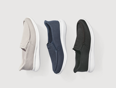 Drei Paar Slipper in Beige, Blau und Schwarz mit weißer Sohle nebeneinander auf hellem Hintergrund.
