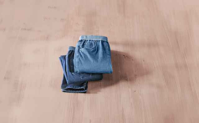 Zwei gefaltete blaue Jeanshosen liegen auf einem hellen Holzboden.