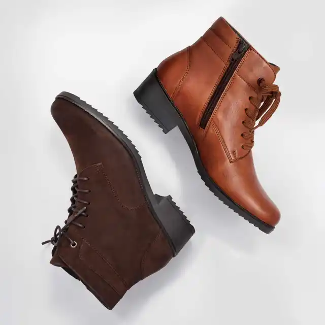 Zwei Schnürstiefel, einer aus braunem Leder, der andere aus dunkelbraunem Wildleder, liegen nebeneinander auf hellem Hintergrund.