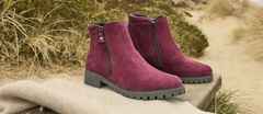 Bordeaux Stiefeletten aus Wildleder mit Reißverschlüssen, auf einer Decke im Freien platziert, umgeben von Gras und Sand.