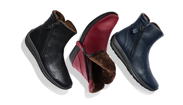 Drei Paar Stiefeletten in Schwarz, Rot und Blau mit seitlichen Reißverschlüssen und warmem Futter, auf weißem Hintergrund schweben.